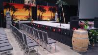 Trade show stage with runway, sunset backdrop, palm tree's and colored bistro lights